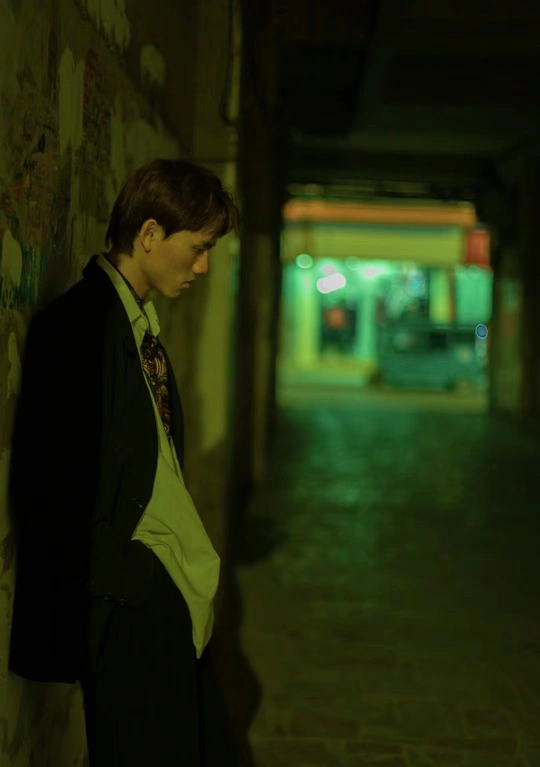 一个穿着西装打领带的青年男子站在一个黑暗的隧道里 正看着一个靠在墙上的女子。