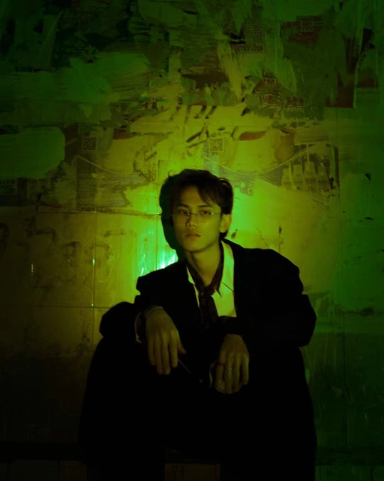 一个穿着领带的年轻人站在一个黑暗的房间里