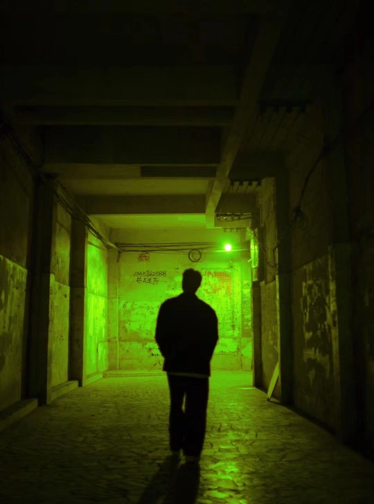 一个站在黑暗隧道里 有绿色灯光的男子