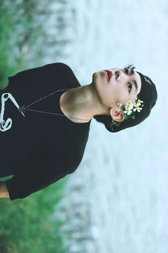 一位穿着黑色连衣裙 手臂上有花的水帘洞前少女