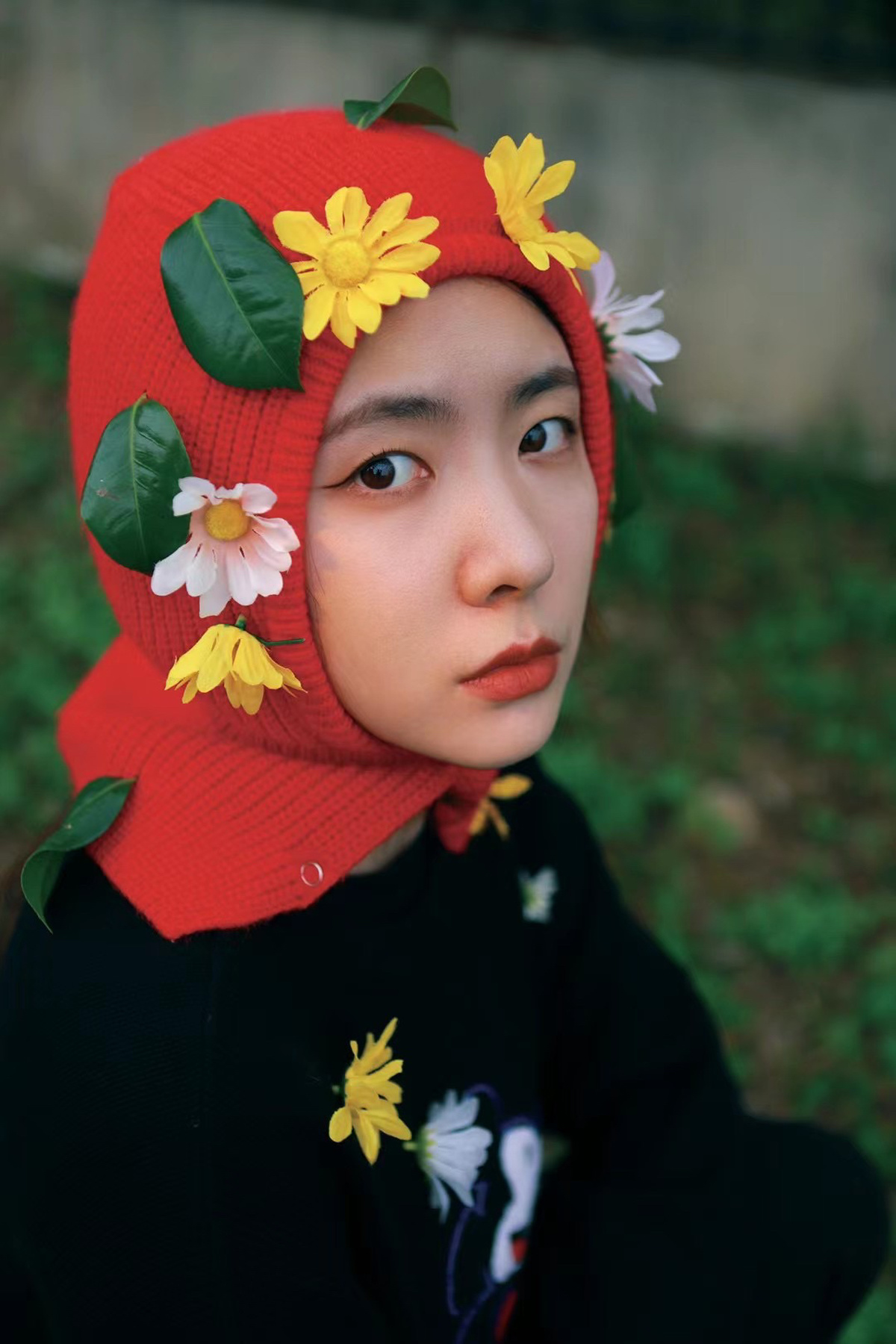 一个戴红帽子上长着花的年轻男孩