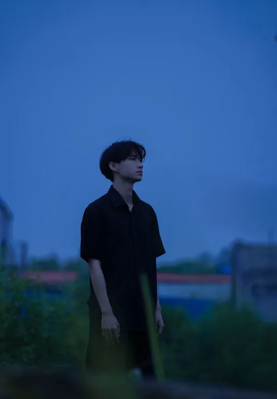 站在草地上 一个年轻人夜晚向远方望去