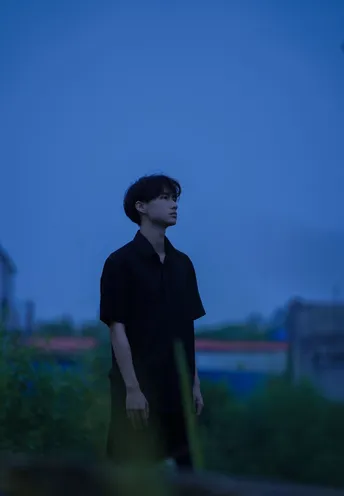 站在草地上 一个年轻人夜晚向远方望去