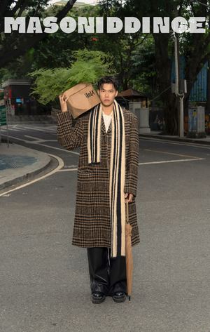 一个穿着长大衣和帽子站在街中间拿着纸袋的男人