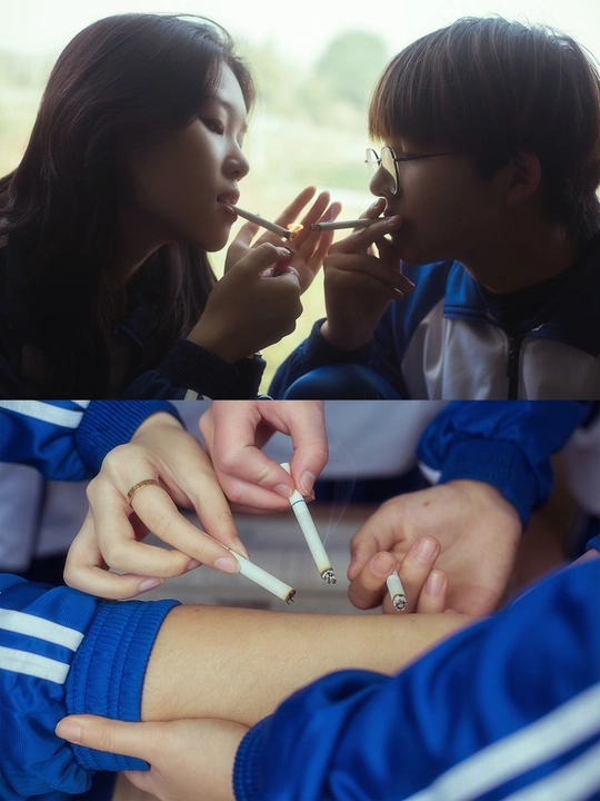 一个小女孩在旁边的一个穿校服的男孩旁边点燃了一支香烟。