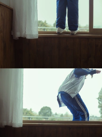 一个年轻人站在窗台上向外看 看到一个孩子从窗户跳出来。