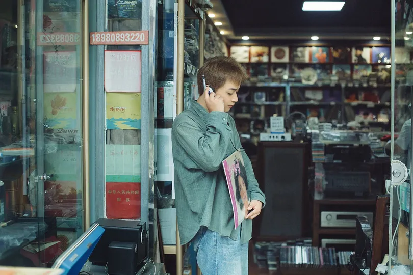 一个年轻人站在商店里打电话