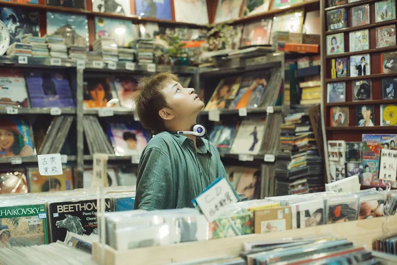 一个年轻的男孩站在一张桌子旁 书店里看着书。