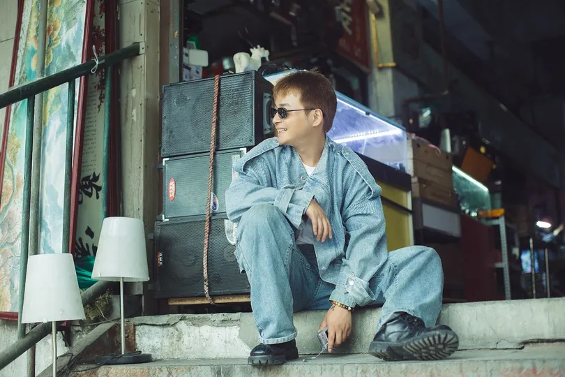 一个戴眼镜的年轻人坐在一些台阶上 前面是一座建筑。