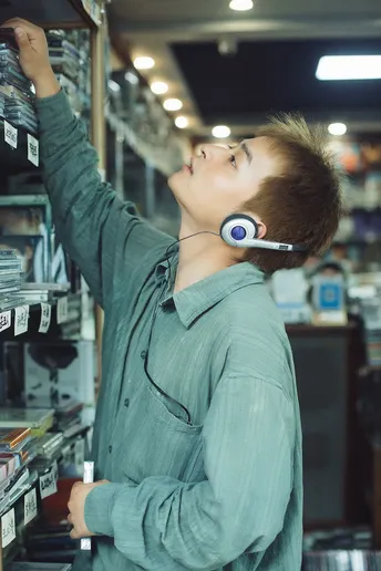 一个戴耳机 young man 站在商店里听音乐