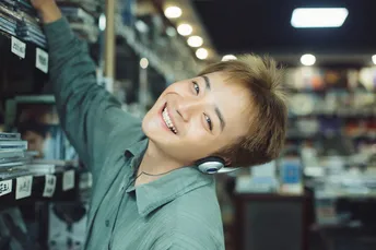 一个年轻男子站在商店里 头上顶着一个男孩 正在看一个架子上的东西。