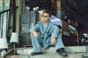 一个戴眼镜的年轻人坐在台阶上摆姿势