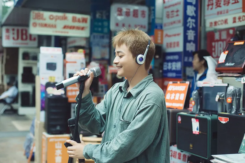 一个戴着耳机唱歌的年轻人 对着麦克风唱歌