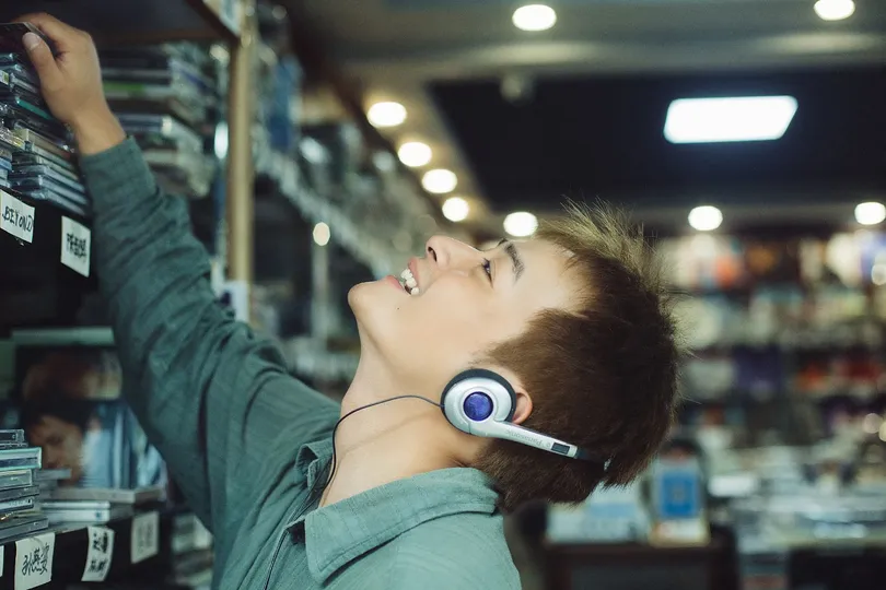 一个戴着耳机 young man 正在商店里看着书架上的书。