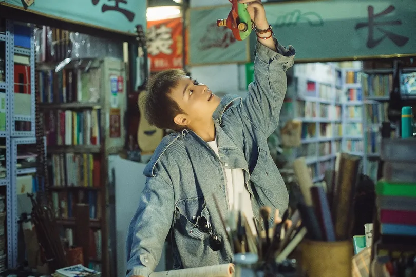 一个年轻男子站在图书馆里 手里拿着一本书 还有一个年轻男孩。