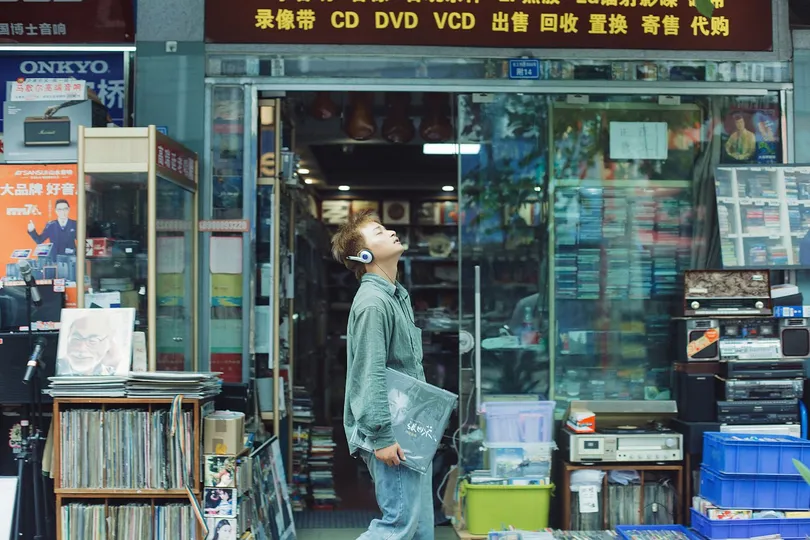 一位妇女走在人行道上 商店前站着一位男子。