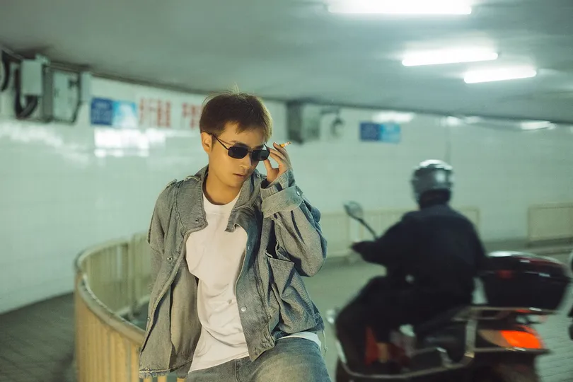 一个戴太阳镜的年轻人坐在摩托车上打电话