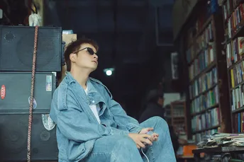 一个戴眼镜的年轻女子坐在图书馆里的一把椅子上 周围堆满了书。