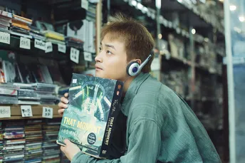 一个戴耳机 young man 正在书店里看着一堆书。