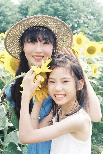 一位年轻女子抱着一个小女孩在向日葵花田里拍照