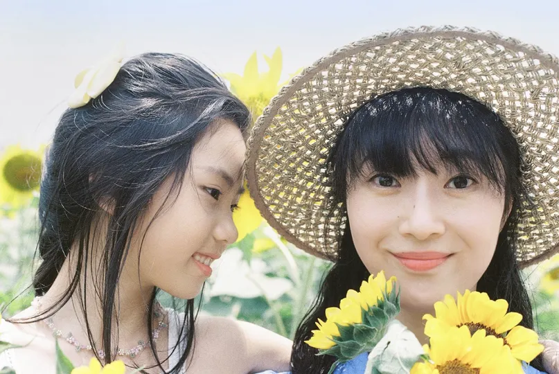 一些戴着帽子的年轻女性站在向日葵田里