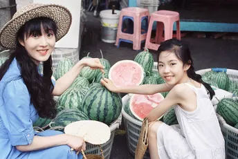 两个戴帽子的小姐在市场前拿着水蜜桃和篮子。