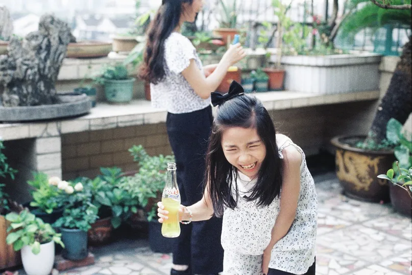 一位年轻女子抱着一个饮料站在一个小女孩旁边