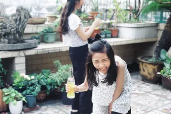 一位年轻女子抱着一个饮料站在一个小女孩旁边