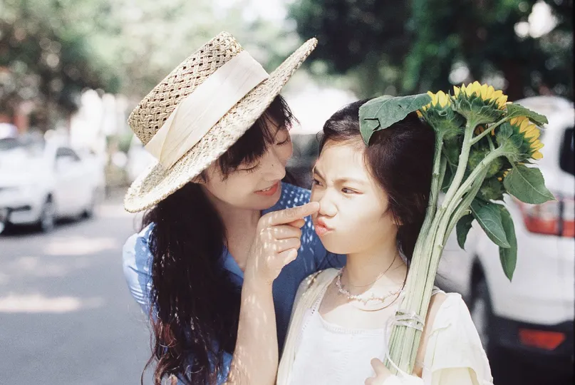 两个年轻女子在街上拿着花。