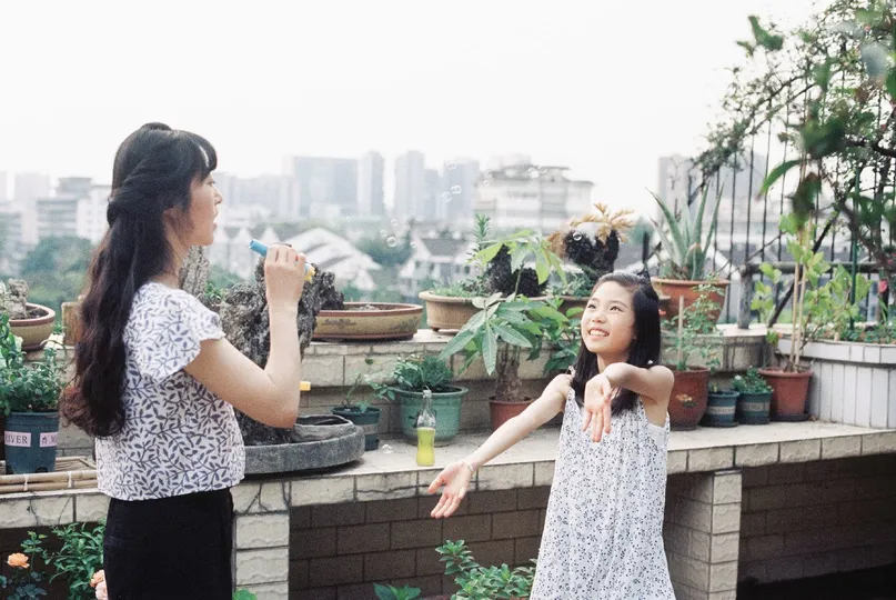 一位年轻女子站在屋顶上 小女孩在玩耍。