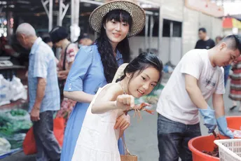 一位年轻女子抱着一个小女孩站在市场旁边的一个男子旁边。