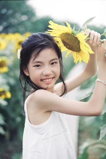 一个小女孩举着向日葵在头上