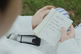 一张照片 一个人手里拿着一本书 书上有字条。