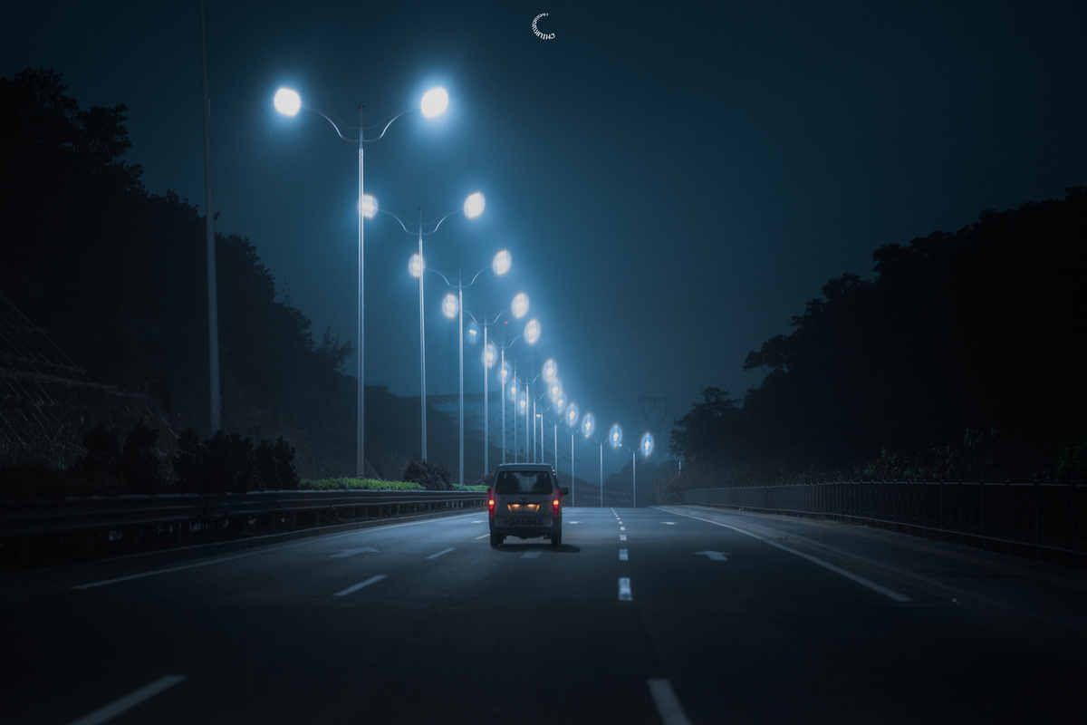 一辆汽车在夜间开着前灯在黑暗的高速公路上行驶 道路上亮着路灯