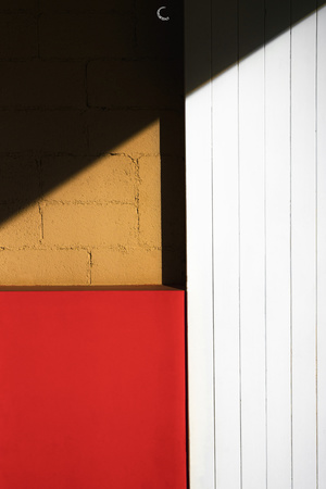 黄色墙上的红色消防栓 旁边是白色的门和阴影