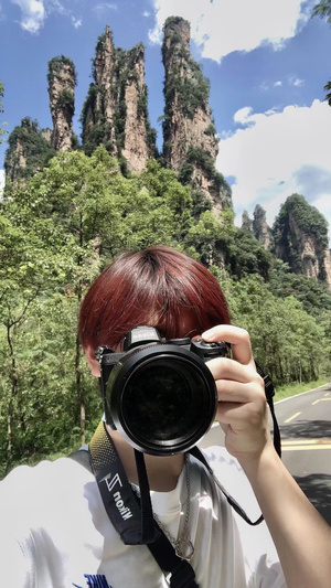 一位女士拿着相机给山脉拍照