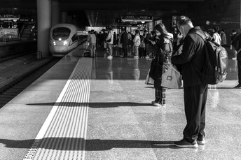 一张黑白地铁站的照片 有 couple of 人在站台上站着。