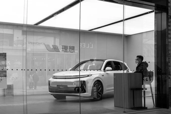 一张黑白照片 一位男子站在一辆车旁边。