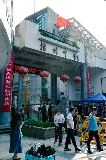 人们带着行李在街上走在一栋楼前