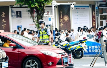 一群人站在路边 一名骑摩托车的警察站在一辆红色轿车前