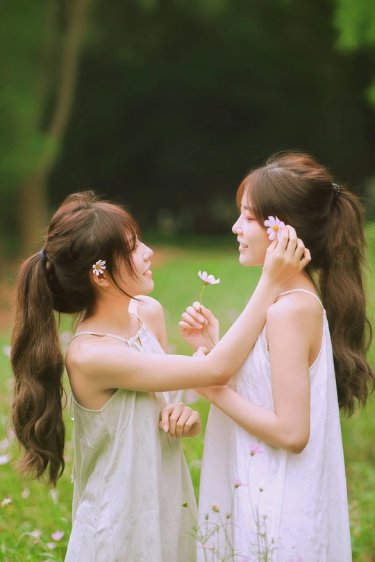 一个年轻的女人和一个小女孩在田里拿着一朵白花