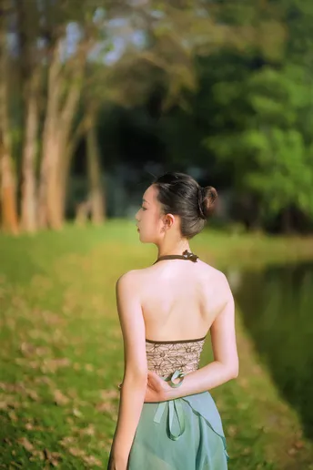 一位穿着蓝色连衣裙的年轻女子正在公园的小径上走