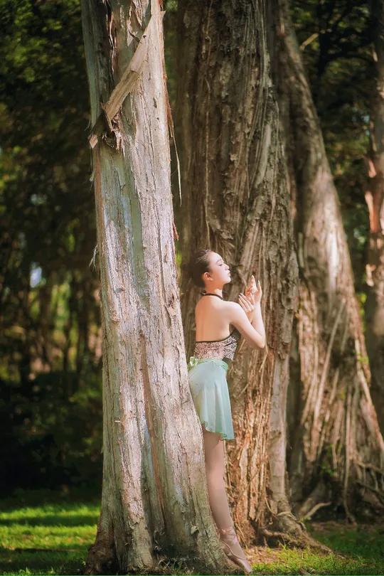 站在森林中的一棵树旁的年轻女子