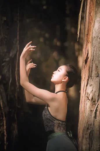 一位在森林中的女人伸出手去摸一棵树。