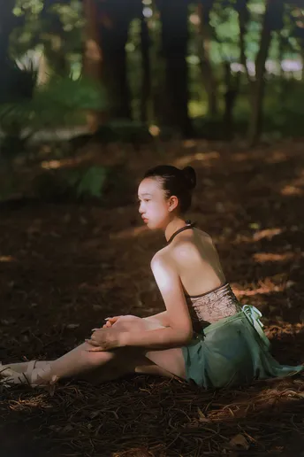 一位穿着绿色连衣裙的年轻女子坐在树木丛生的森林里