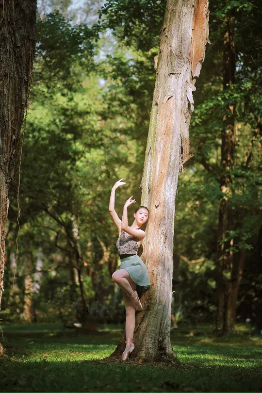 一位年轻女子在森林中攀爬一棵树