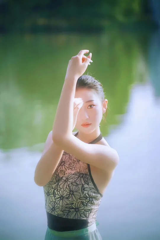 一位年轻女子站在水边 双手举过头顶