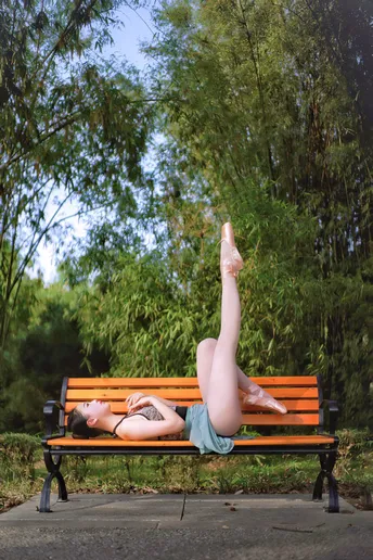 一个人躺在长凳上 双腿向上伸展 而另一个人则躺在公园里的长凳上。