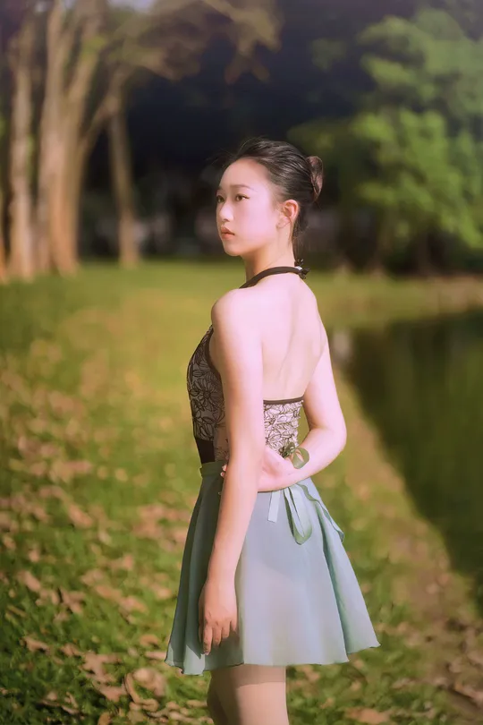 一位穿着蓝色连衣裙的小女孩站在公园里