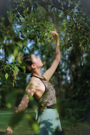 站在森林中一棵绿树下的年轻女子